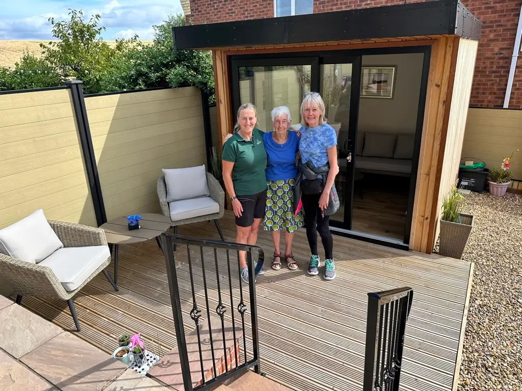 small garden room clad in thermowood, picture with happy customers.